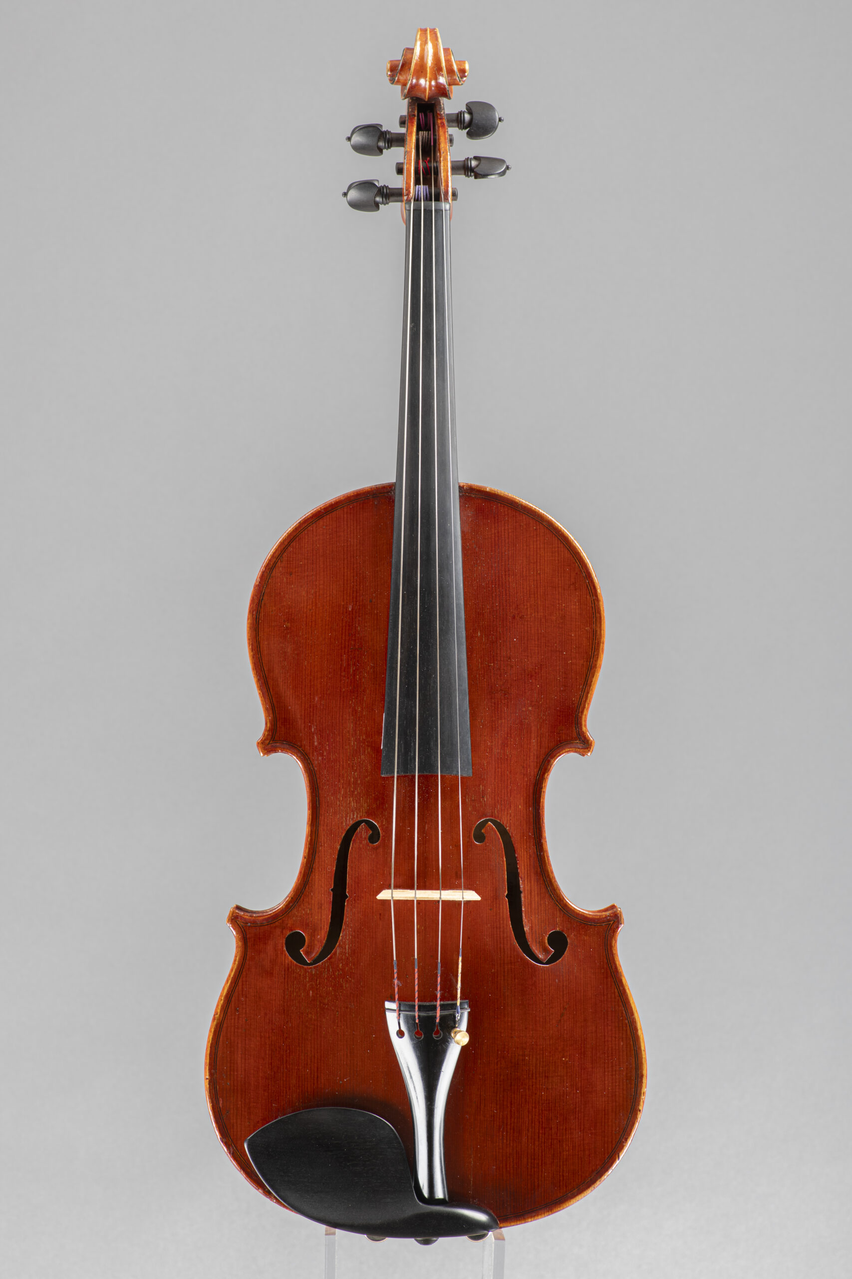 An upright, centered shot of a classic violin against a neutral grey backdrop, highlighting its polished wooden body and ebony fingerboard.