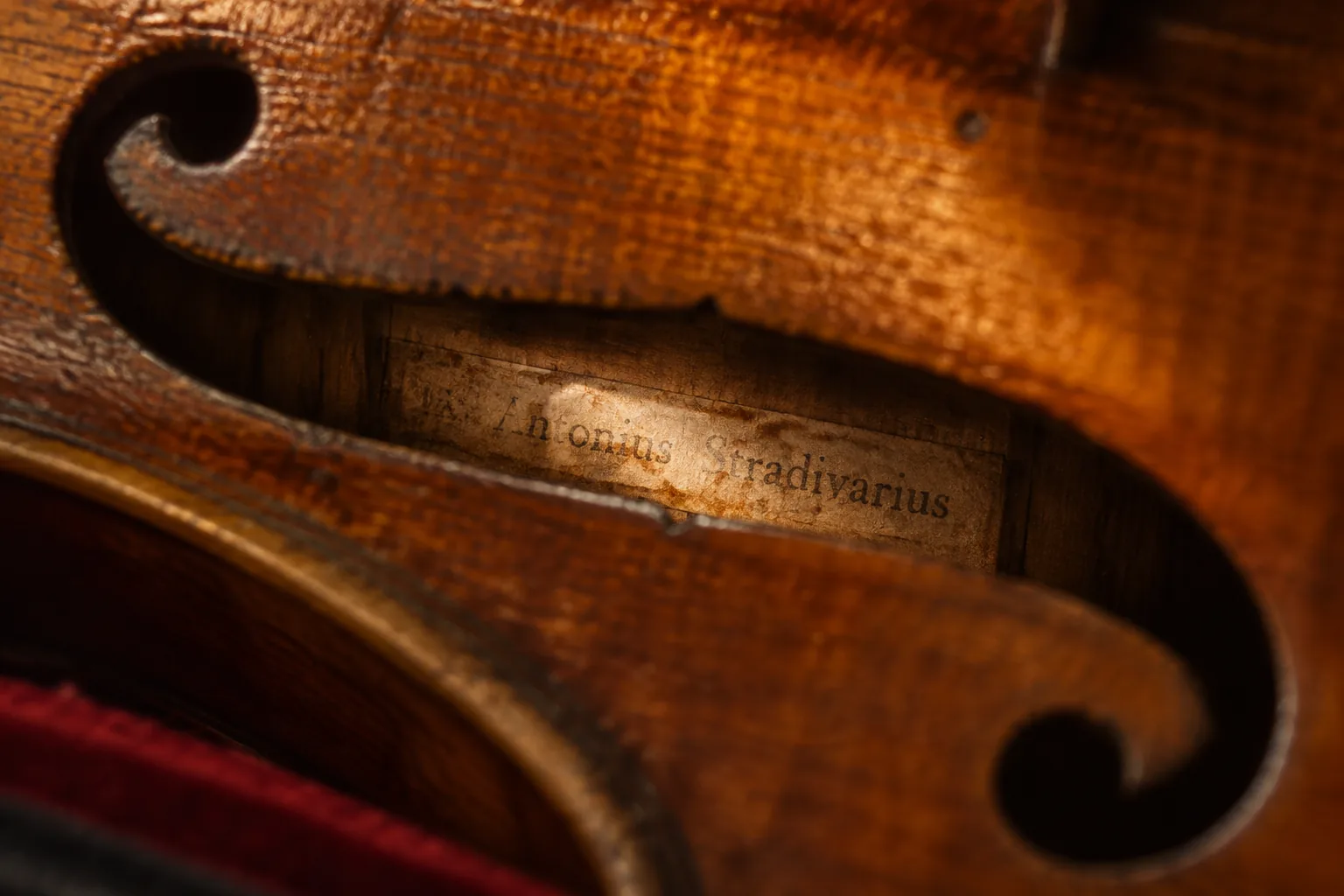 View through a violin f-hole of a yellowed label reading Antonius Stradivarius inside an old German trade instrument